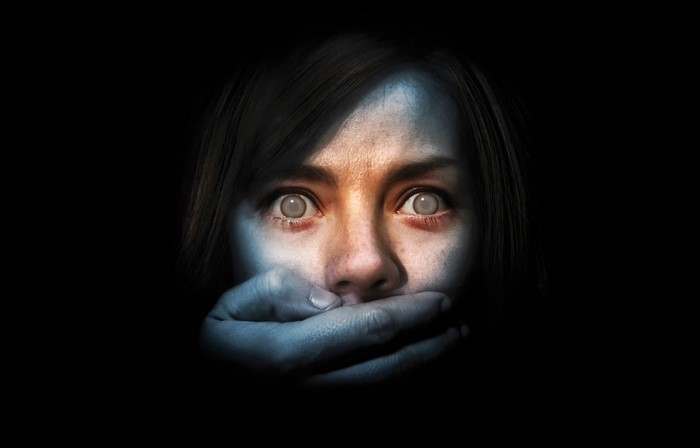 Woman with hand over mouth in darkness