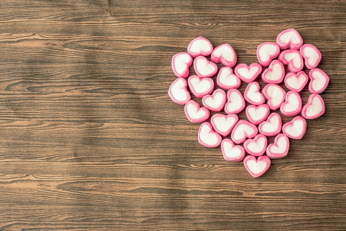 Heart shape made of pink and white marshmallows on a wooden background