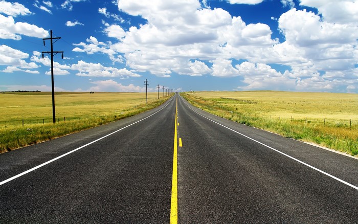 Empty highway stretching into the distance under a cloudy sky