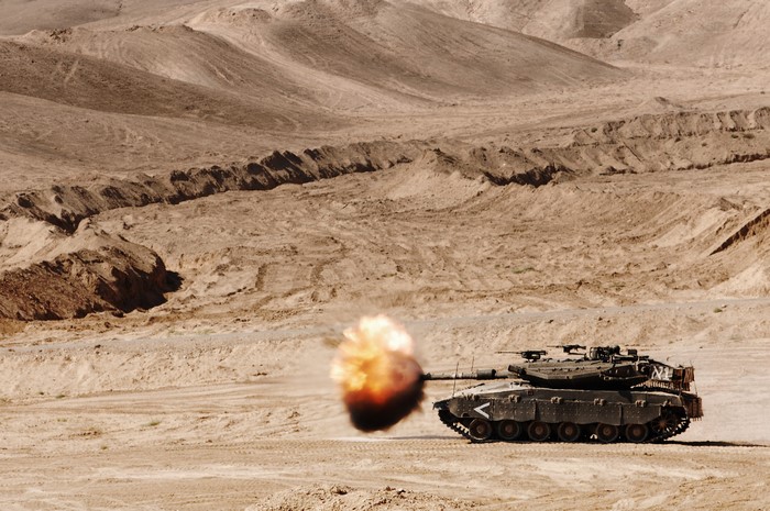 Merkava tank firing in a desert landscape