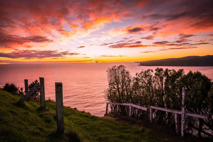 Sunset over the ocean with clouds and fence