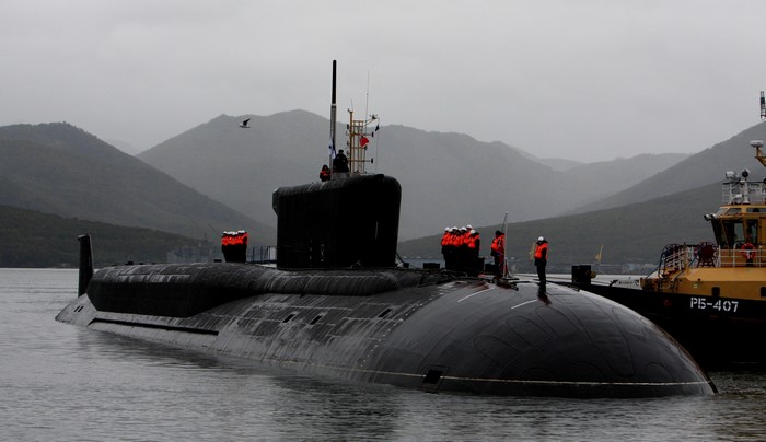 Borei-class submarine docked near a tugboat