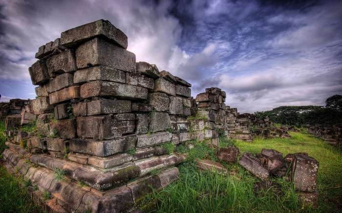 Ancient stone ruins overgrown with grass under a cloudy sky