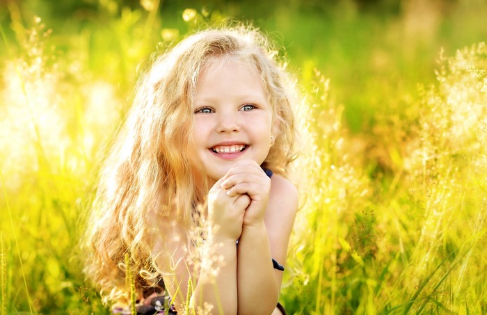 Blonde girl smiling in a sunny field