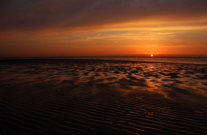 Sunset over the sea with rippled sand