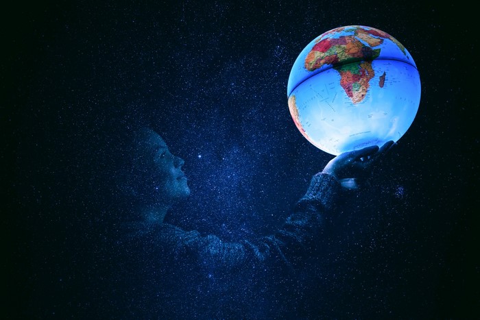 Person Holding Illuminated Globe Amid Starry Night