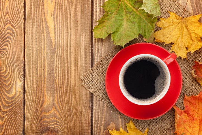Coffee cup with maple leaves on wooden table