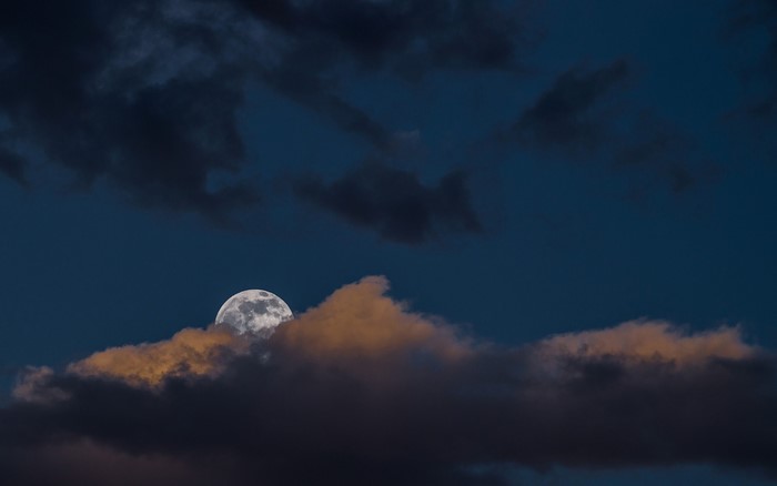 Full moon behind clouds at dusk
