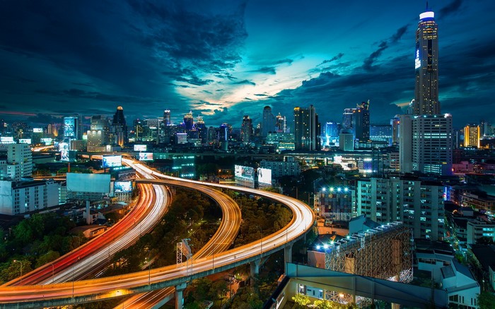 Nighttime cityscape with illuminated highways and skyscrapers