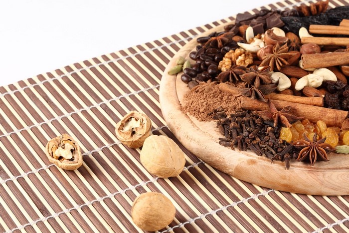 Assortment of nuts, spices, and chocolate on a wooden board