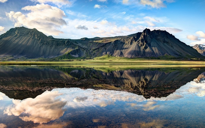Mountain range reflected in a calm lake under a cloudy sky