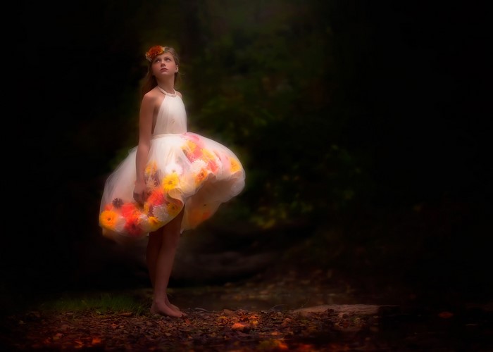 Girl in a flower dress in a dark forest