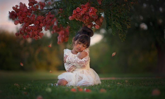 Little Asian girl in white dress under tree branches