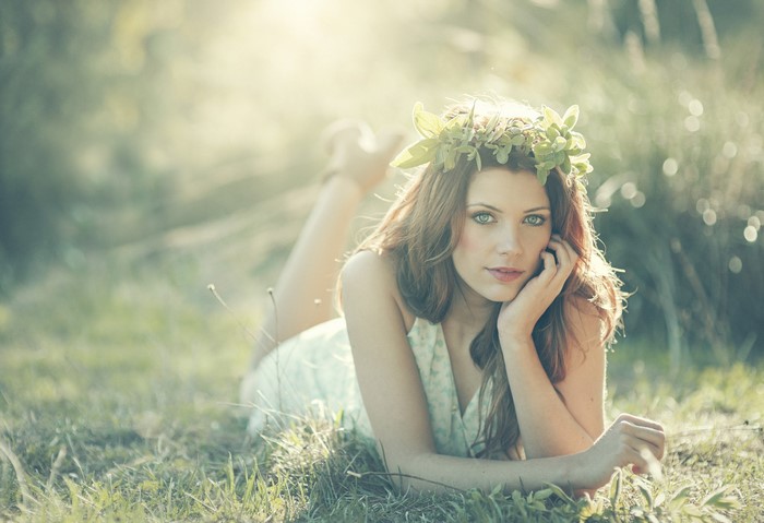 Woman with flower crown lying in grass