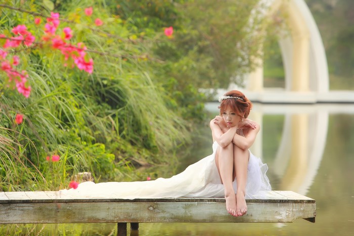 Serene Bride Sitting on Wooden Dock in Nature