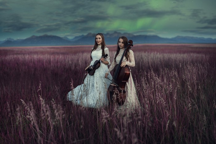 Two women with musical instruments in a field