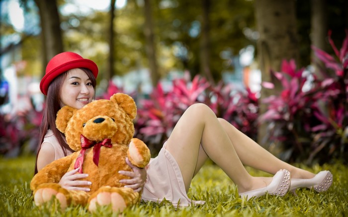 Woman in red hat holding teddy bear outdoors