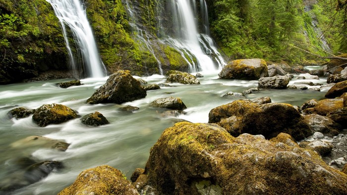 Waterfalls cascading over moss-covered rocks into a river