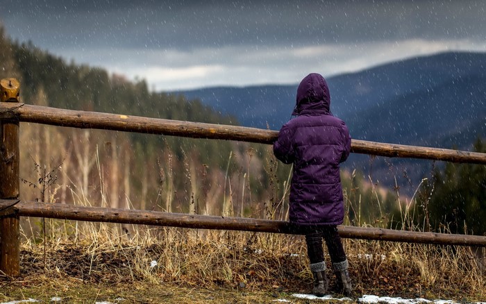 Girl in a purple jacket looking at the rain