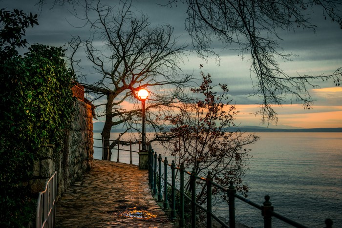 Path by the sea with a lamppost at sunset