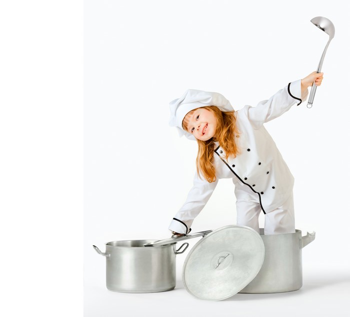Little girl in chef uniform with ladle and pots