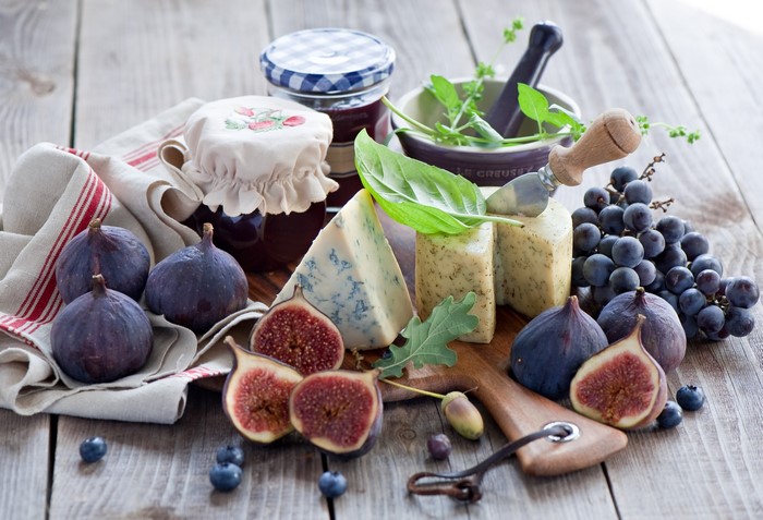 Cheese, figs, jam, grapes, and blueberries on a wooden table