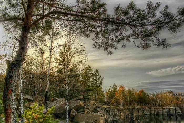 Autumn landscape with trees, rocks, and a building