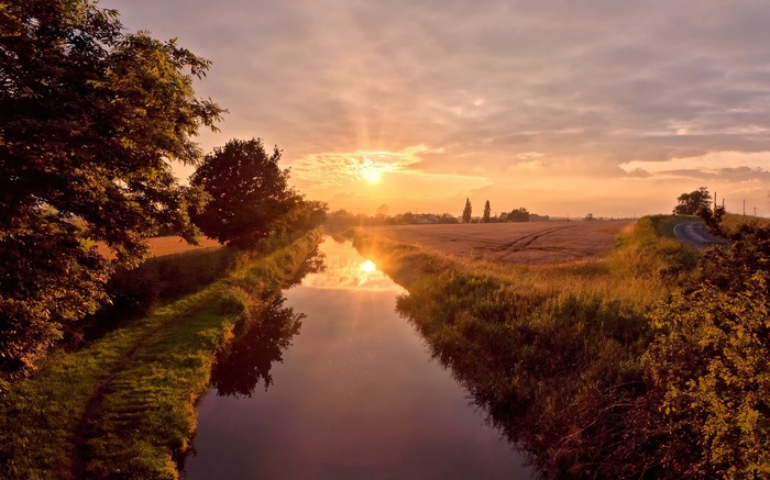 Canal at sunset with fields and trees