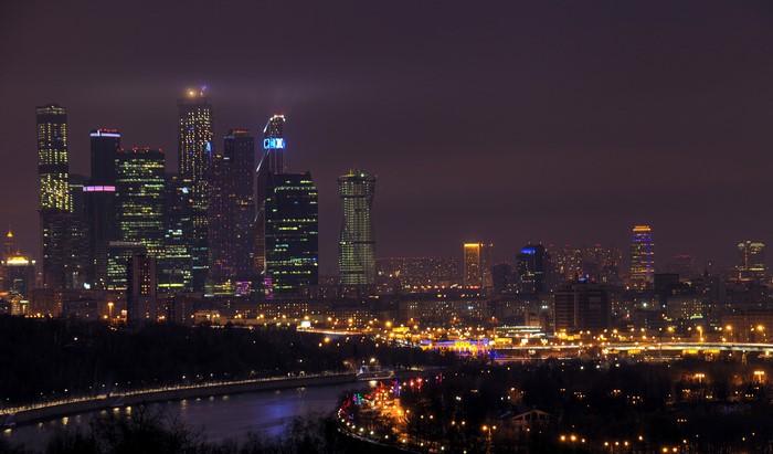 Moscow skyscrapers at night with river and street lights