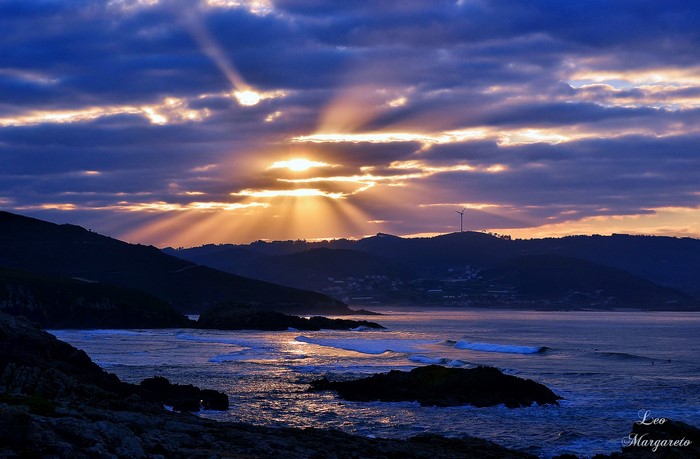 Sunset with sun rays over the sea and hills