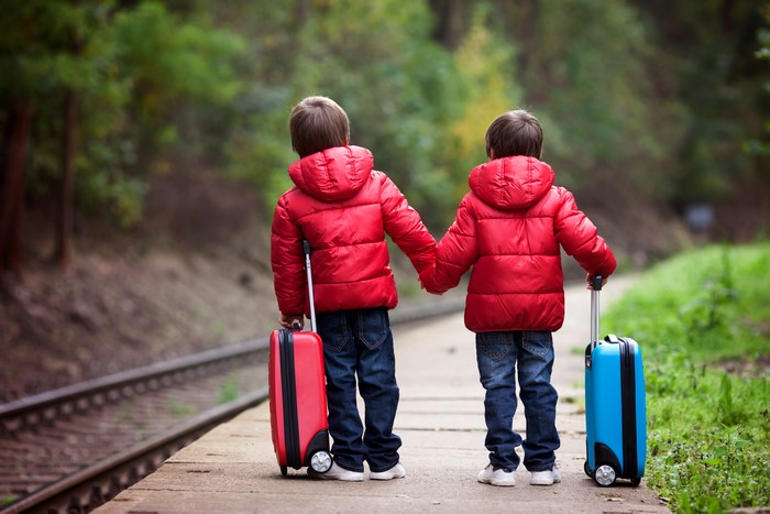 Two boys with suitcases on a railroad platform