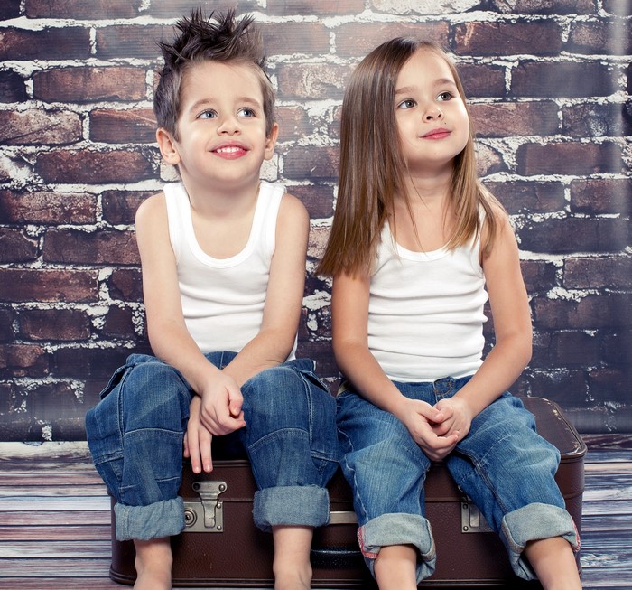 Boy and girl sitting on a suitcase