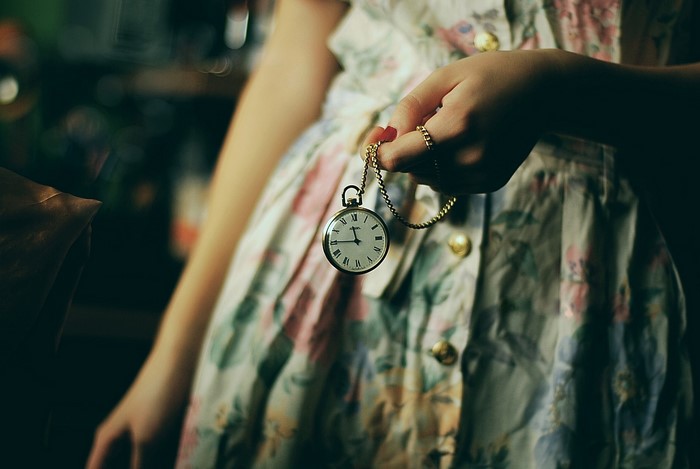 Person holding a pocket watch in a floral dress