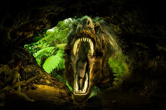 Cave entrance with a roaring Tyrannosaurus Rex and a woman