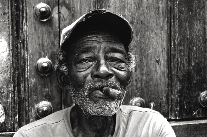 Man with beard and baseball cap smoking cigar