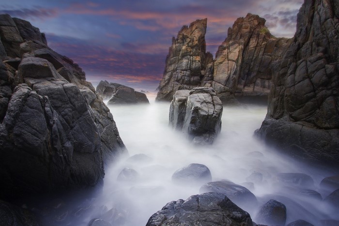 Rocky coastline with misty ocean and dramatic sky