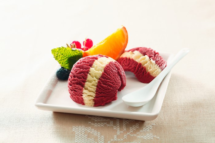 Red and white ice cream scoops with berries and orange slice