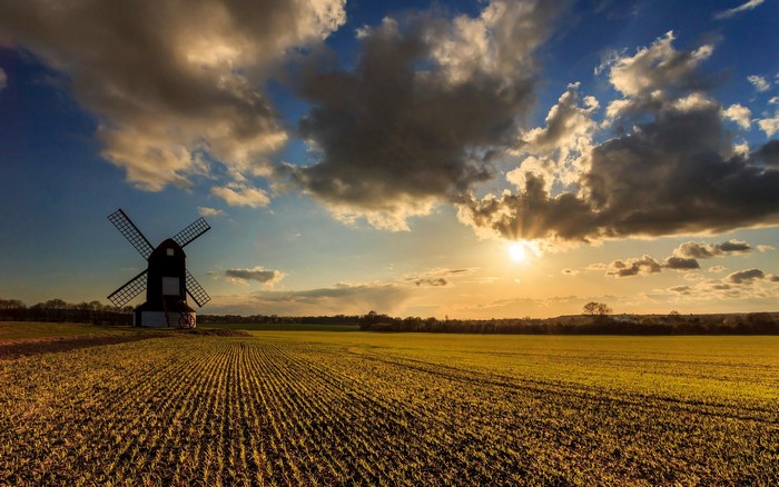 Windmill in a field at sunset with clouds