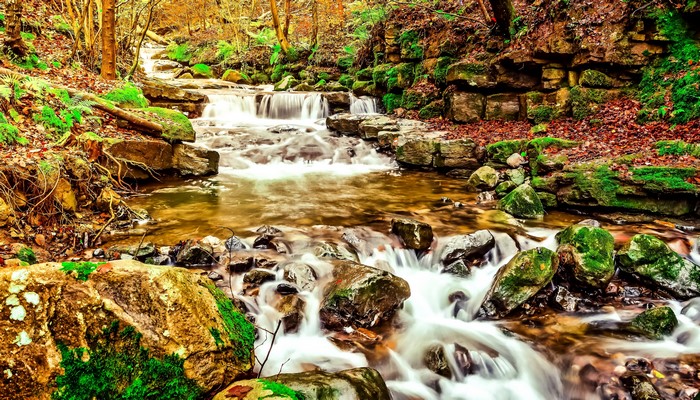 Autumn stream with waterfalls and mossy stones