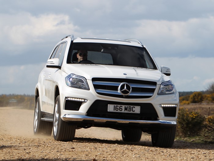 White Mercedes-Benz GL 350 BlueTec AMG Sports Package driving on dirt road