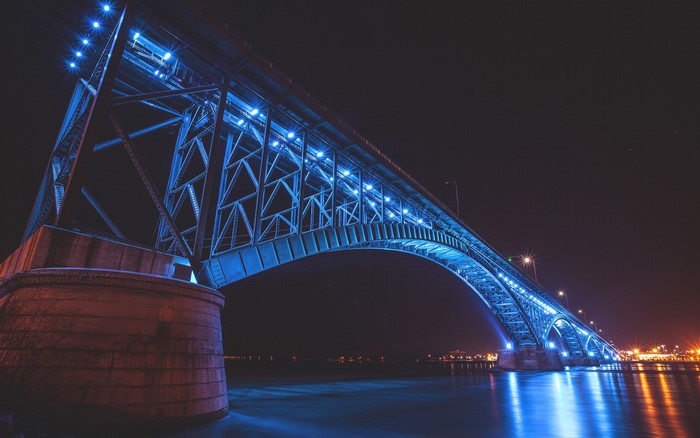 Bridge illuminated with blue lights at night over water