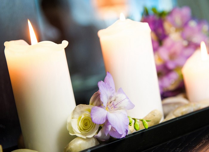 White candles with flowers and stones
