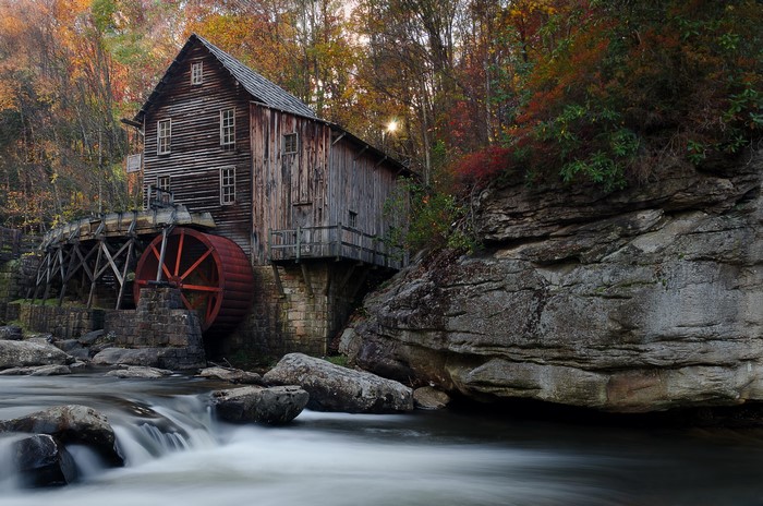 Old wooden watermill by a rocky river in autumn