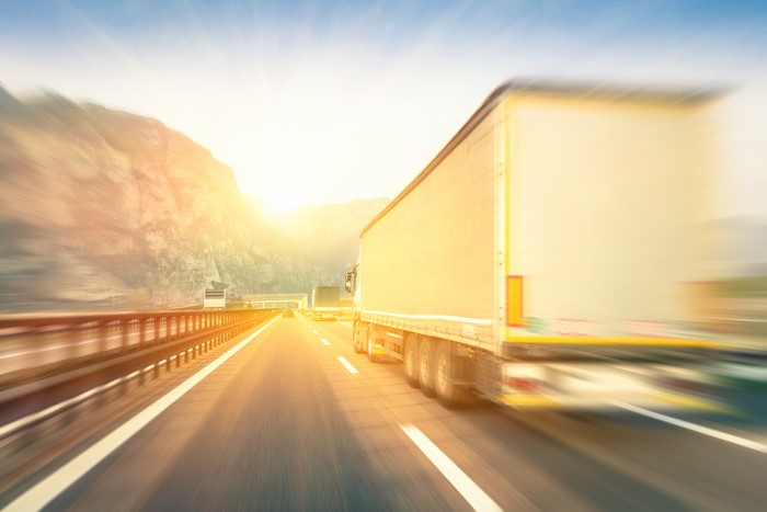Trucks on a highway at sunset