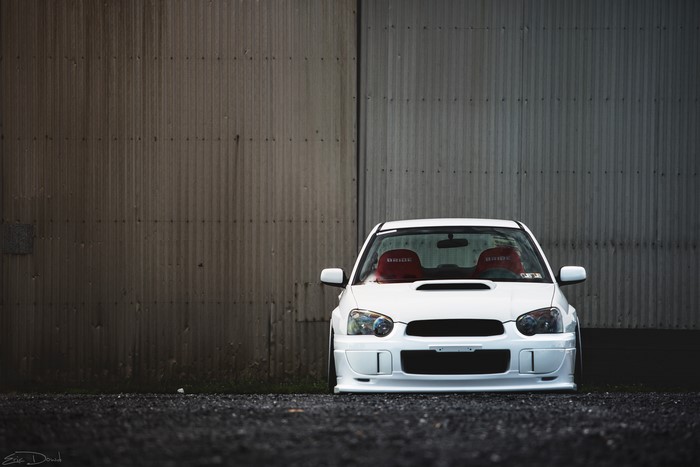 White Subaru Impreza WRX STI parked in front of a corrugated metal wall