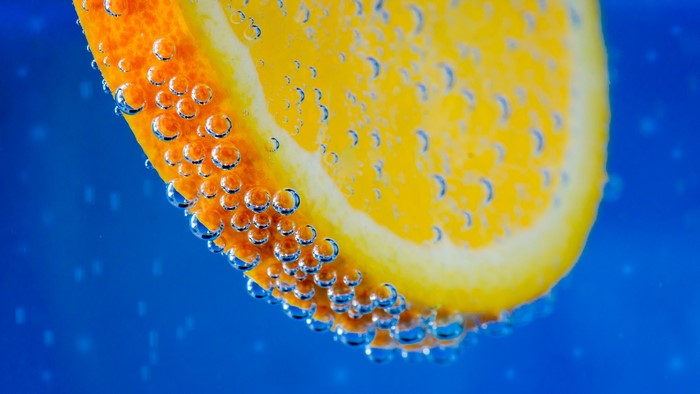 Orange slice with bubbles in blue liquid
