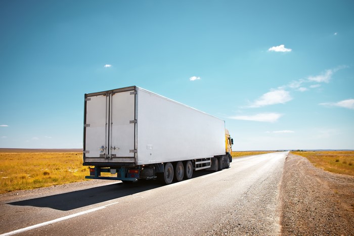 White semi-trailer truck driving on a road