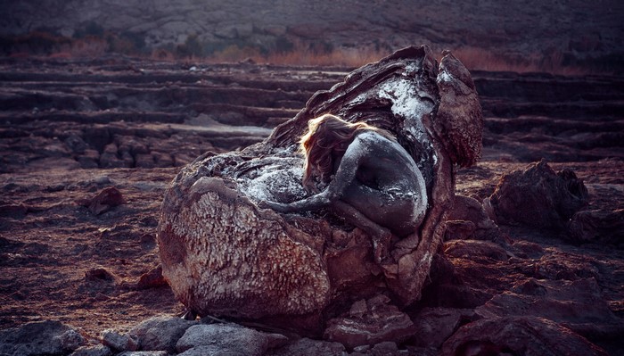 Woman covered in mud in a desolate landscape