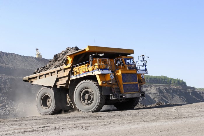 Yellow mining dump truck carrying rocks