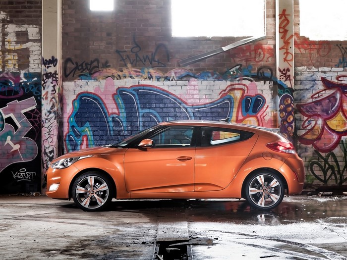 Orange Hyundai Veloster parked in graffiti-covered warehouse